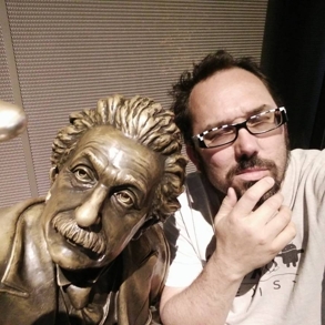 A sculpture of Einstein with a man making a funny pose next to it