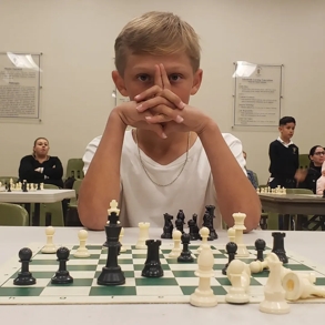 A young kid in front of a chess board